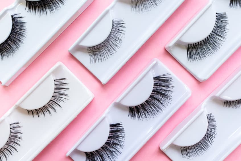 different false eyelashes on a trendy pastel pink background. beauty pattern. makeup accessories. cosmetics products.